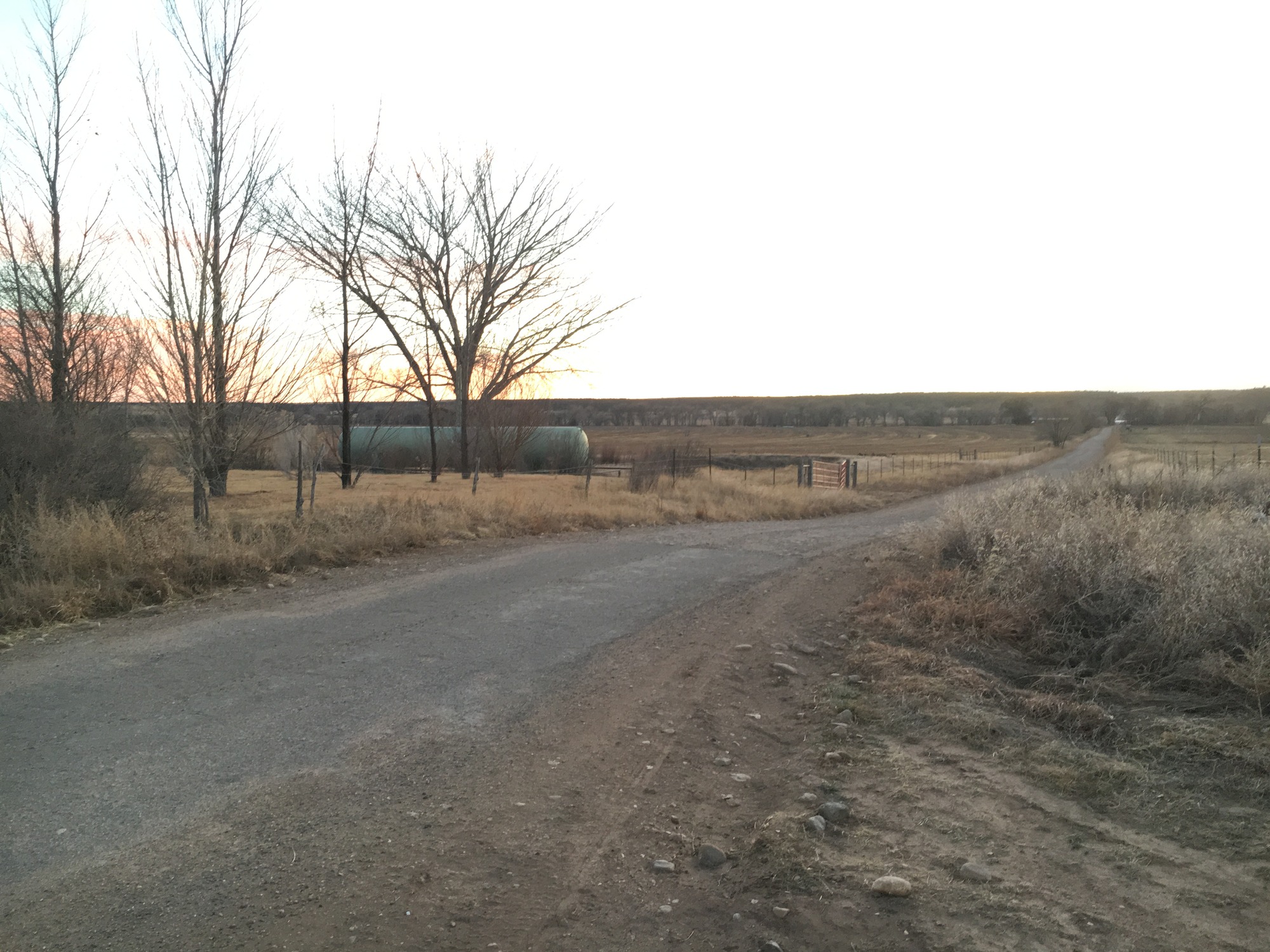 A clean road leading to a tank in the middle of a field.