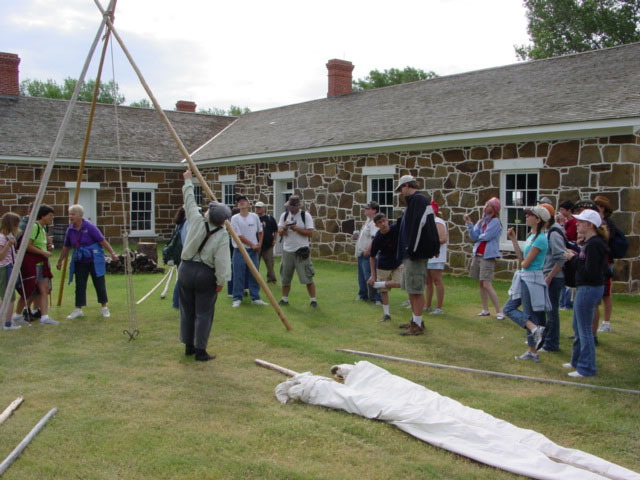 A group of people standing around a teepee.