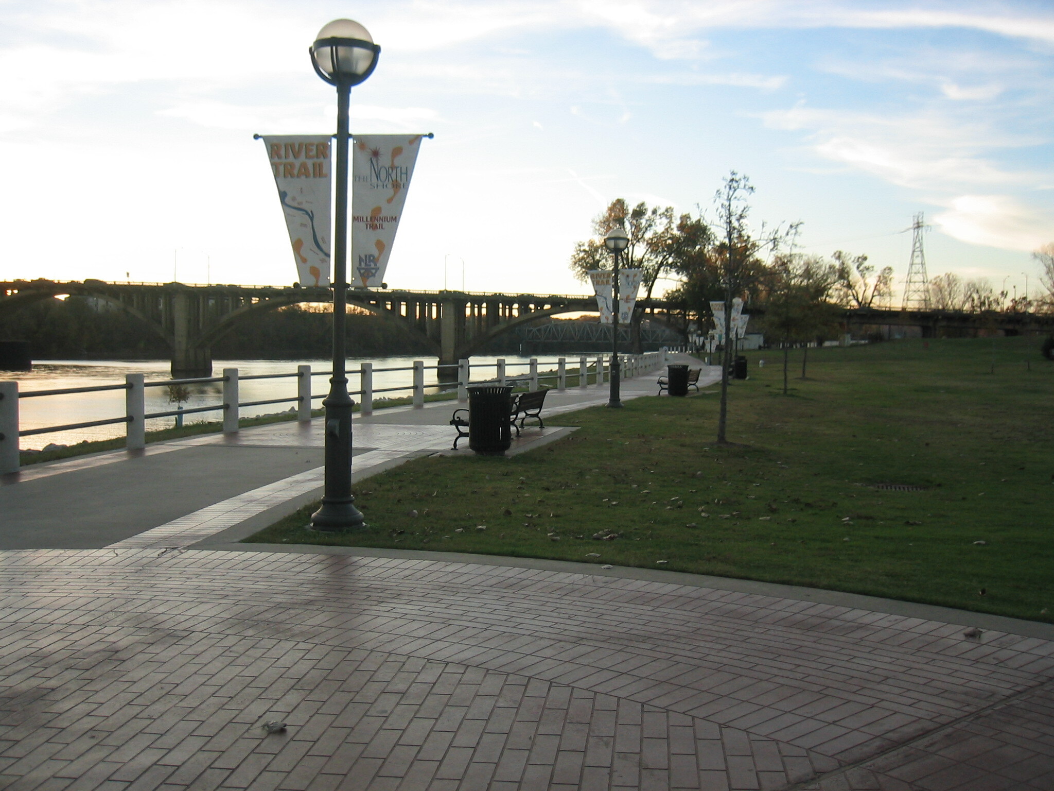 A brick walkway next to a river.