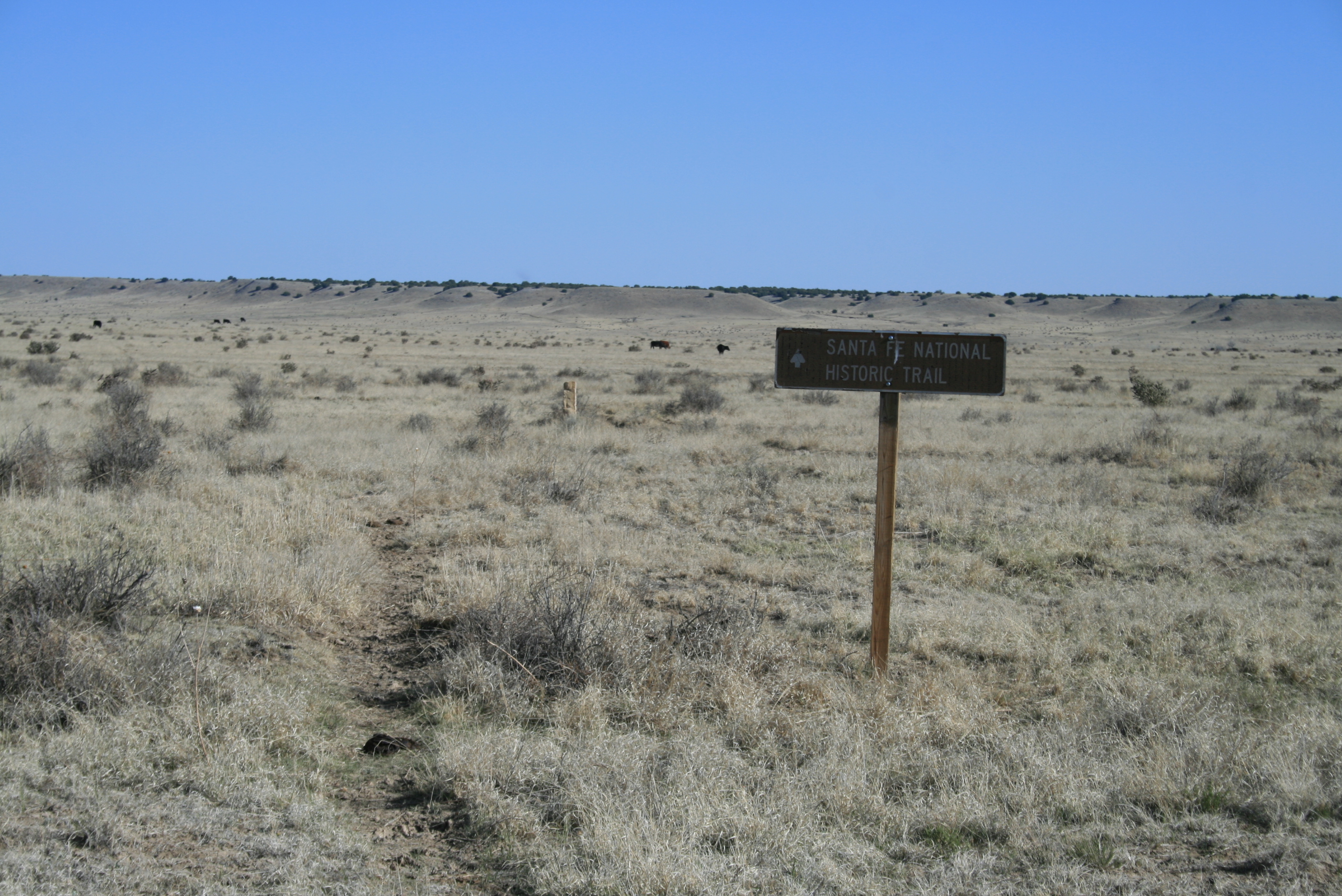 A sign titled "Santa Fe National Historic Trail" in the middle of a field.