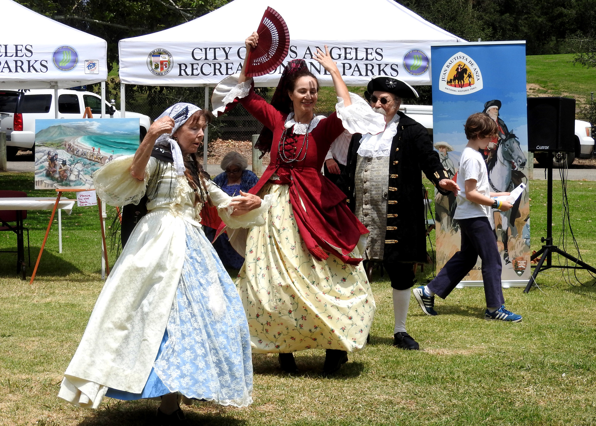 A volunteer living history reenactors dressed as a dancers from colonial Spain perform in front of the informational tables.