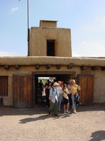 A group of people standing in front of a adobe building.