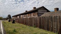 A wooden fence and house on the side of a road.