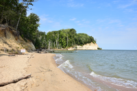 Waves lapping a sandy beach with cliffs in the distance.