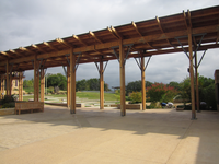 A wooden building with a green lawn and labyrinth garden under a partly cloudy sky.