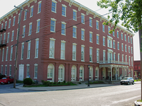 Large, ornate, four story building made of red brick and trimmed in white.
