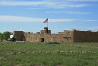 A tan building in a grassy field.