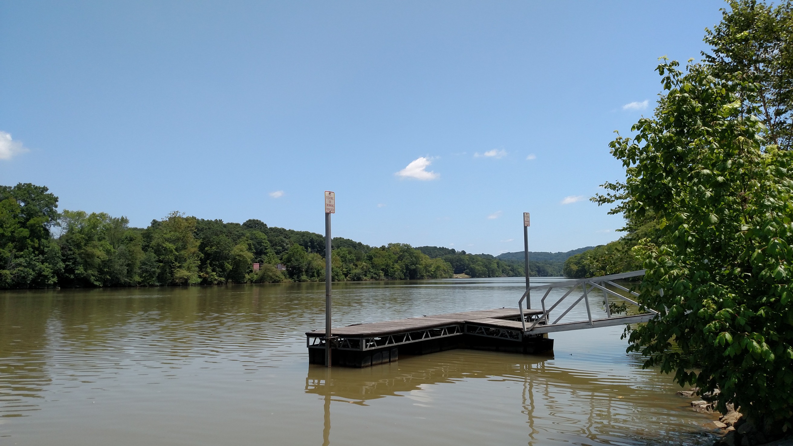 A dock on a body of water with trees in the background.
