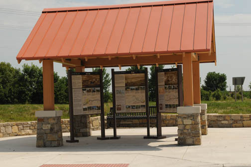 A shelter with a red roof and wayside panels on display.