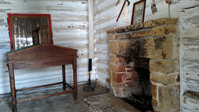 A log cabin with a fireplace and a table.
