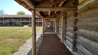 A wooden walkway in front of a log cabin.
