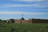 A brown building surrounded by a grassy field with oxen grazing.