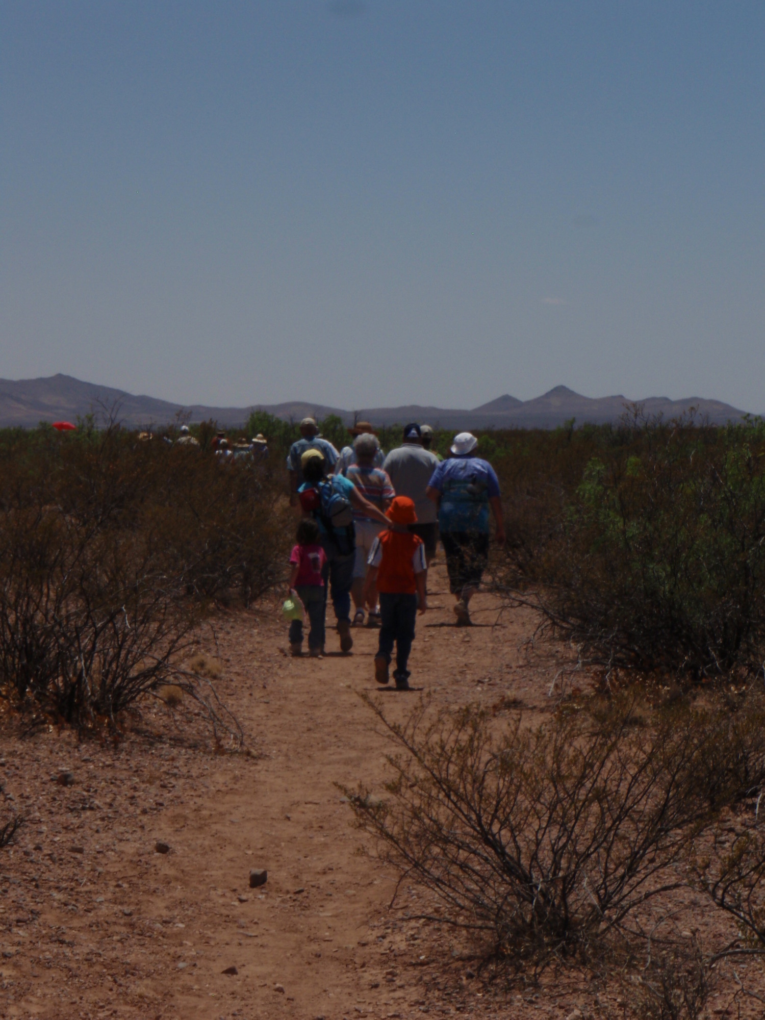 A group of people walking down a dirt path.