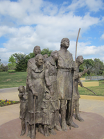 A statue under the open sky with some trees in the background.
