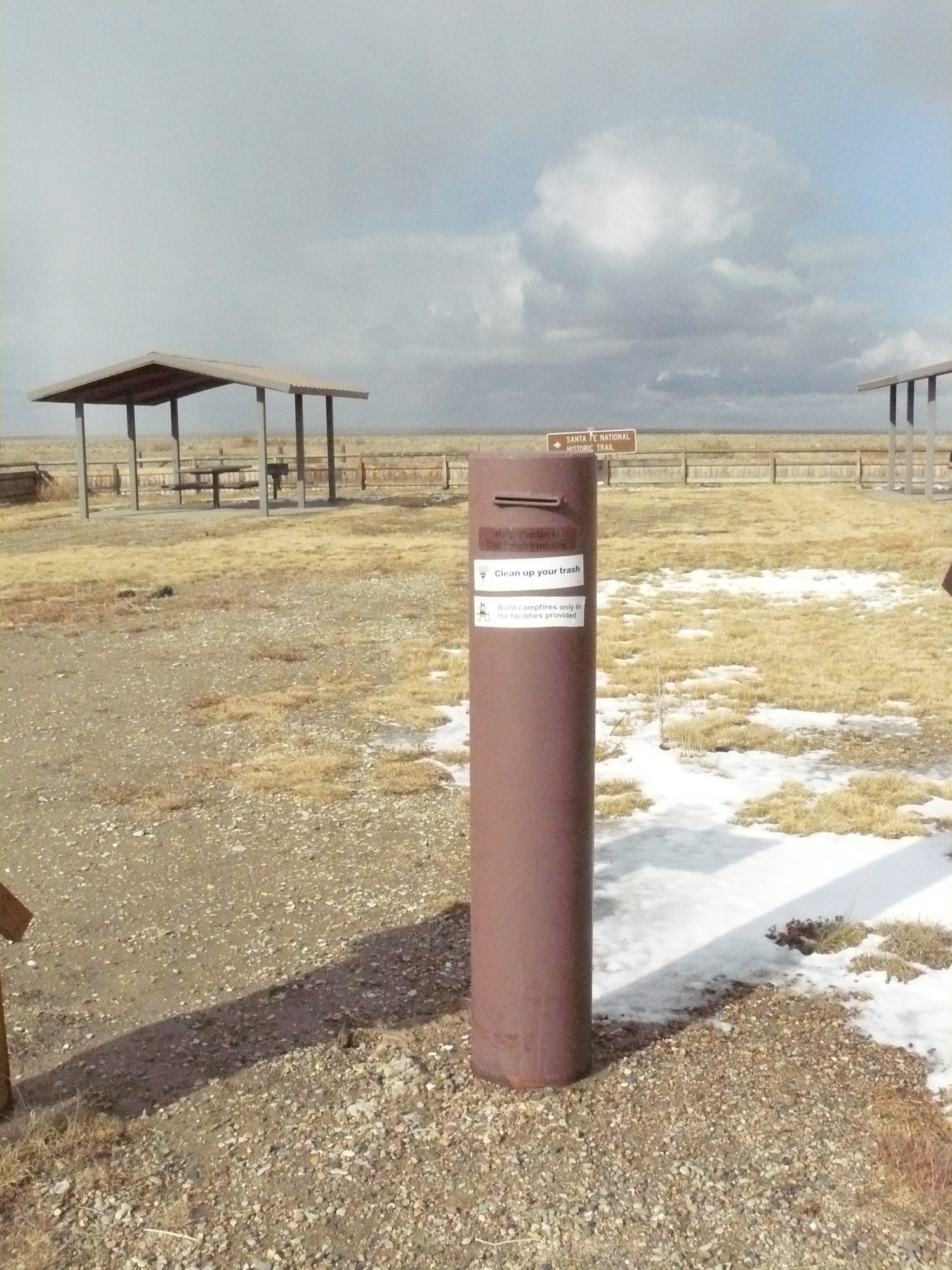 A post in the middle of a field with snow on it.