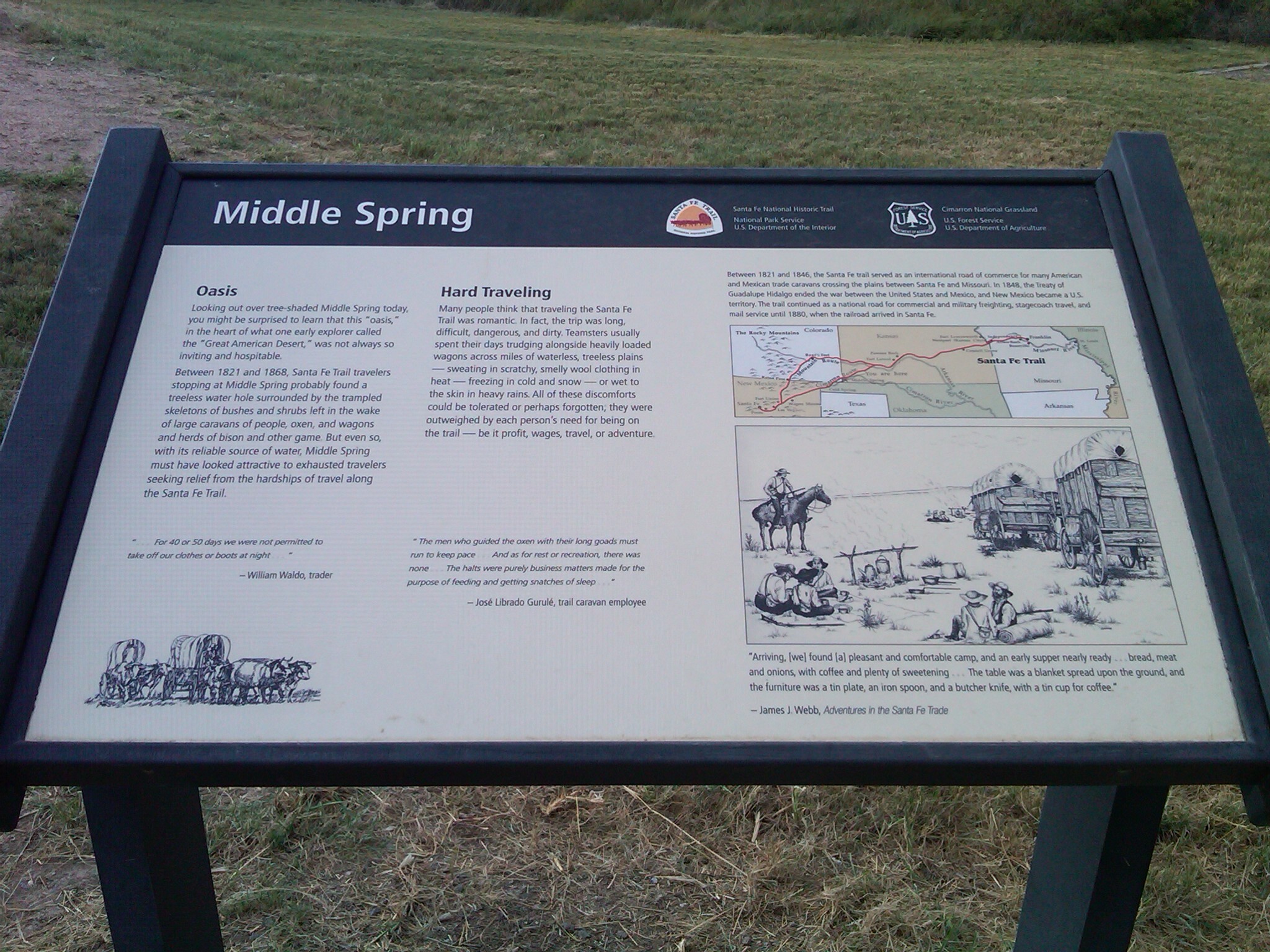 A wayside titled "Middle Spring" with some text and illustration on it in a grassy field.