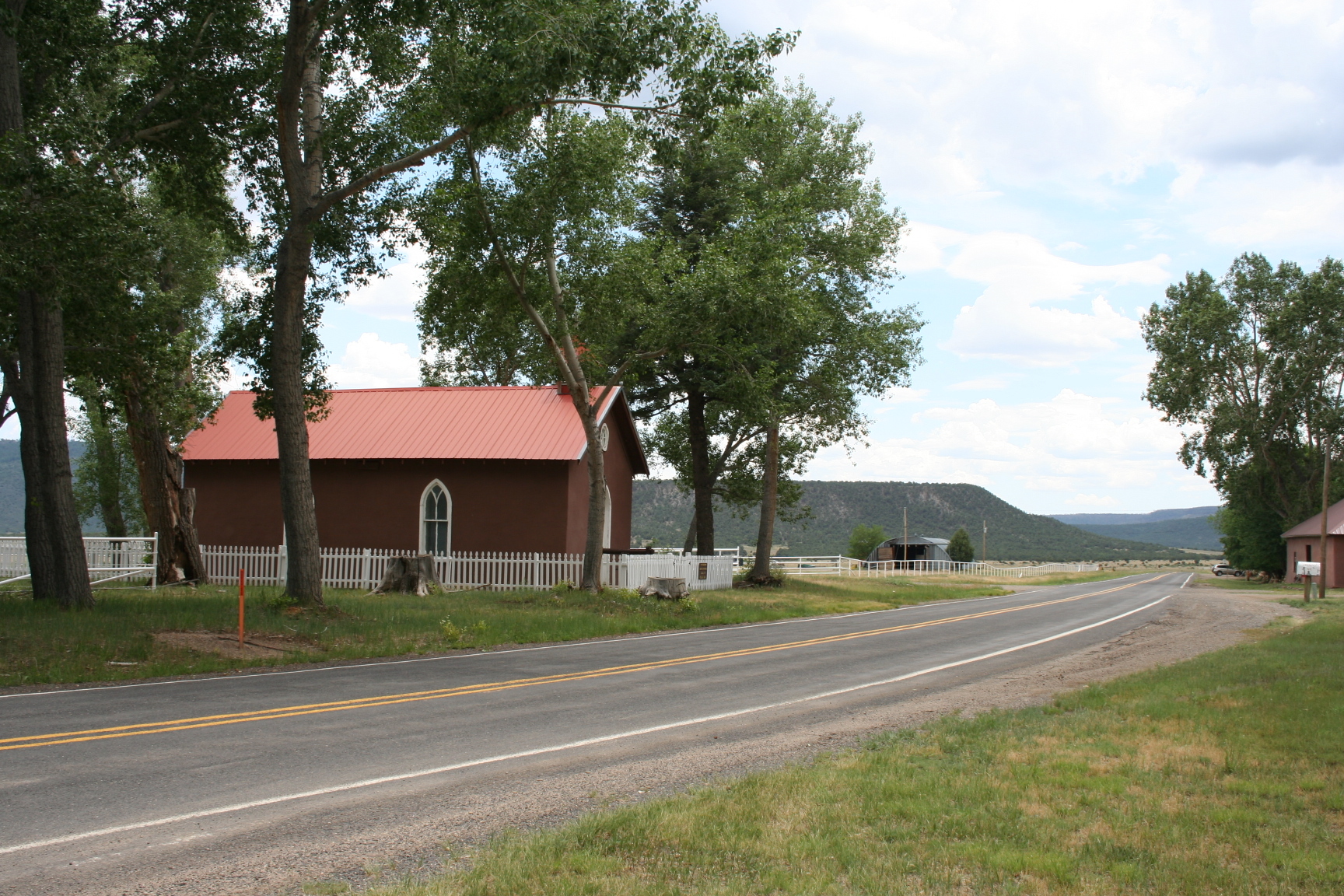 A country road with trees and a farm house