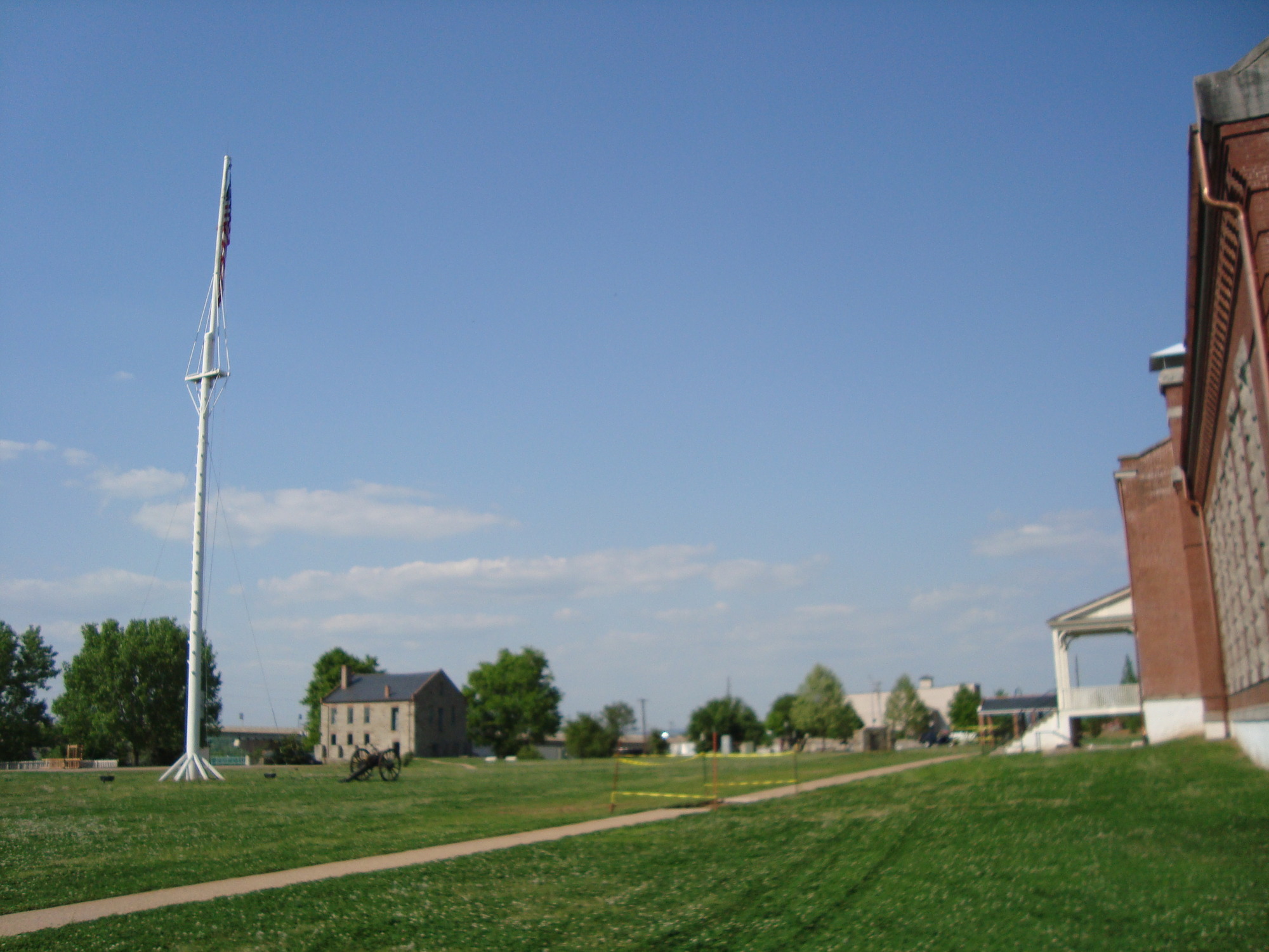 A building with a flag pole in the middle of a grassy field.