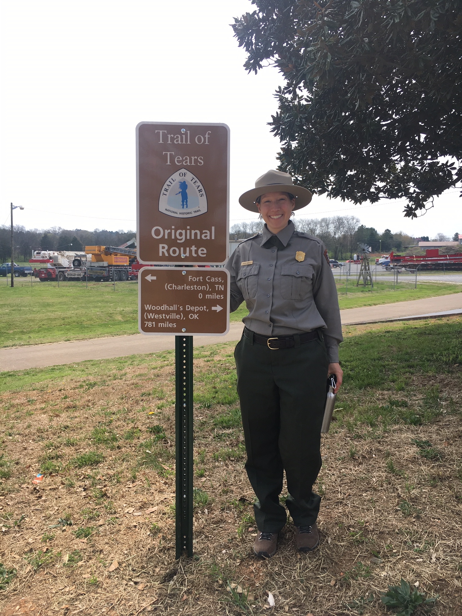 A person standing next to a sign with white text and a logo on it.