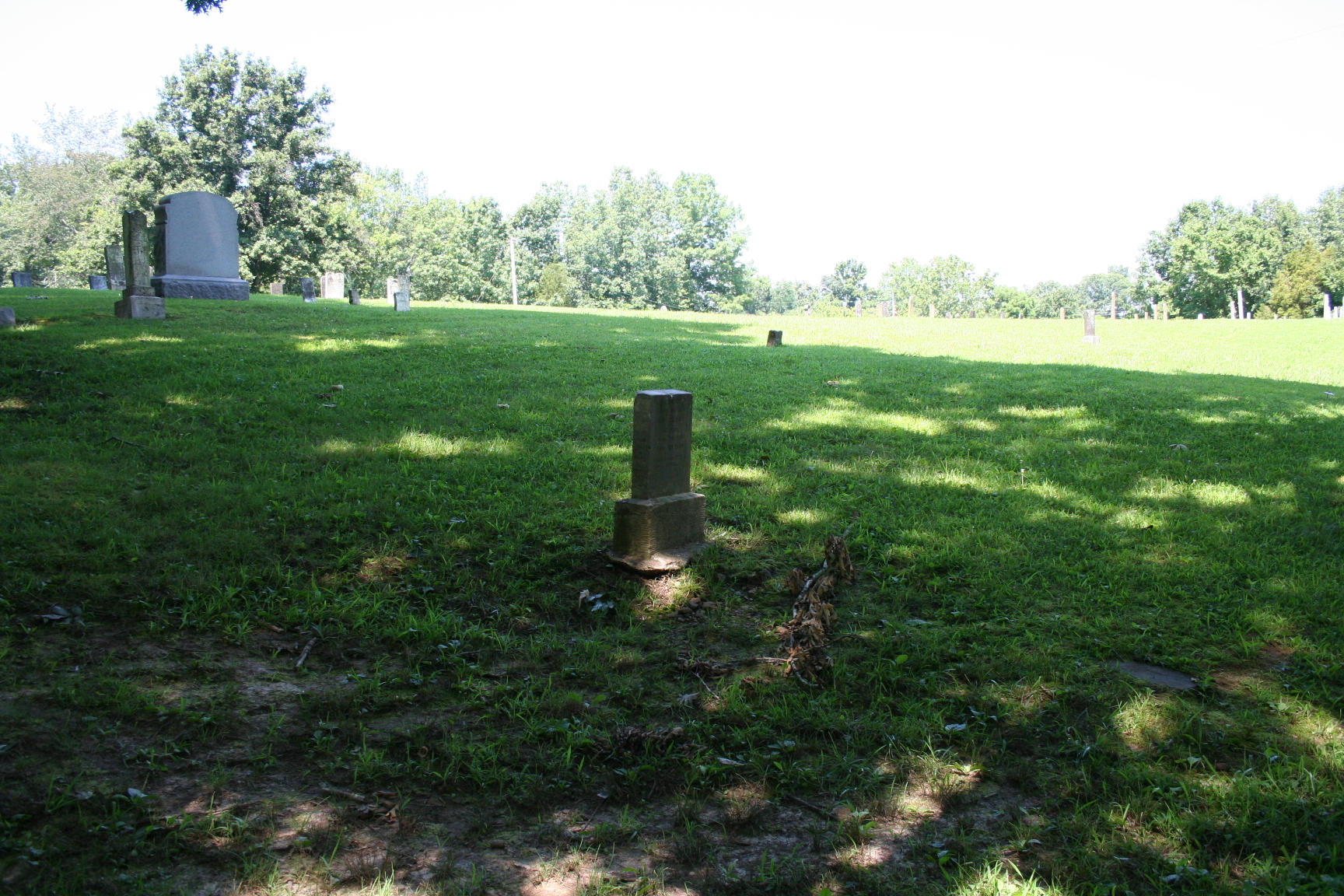 A gravestone in the middle of a grassy field.