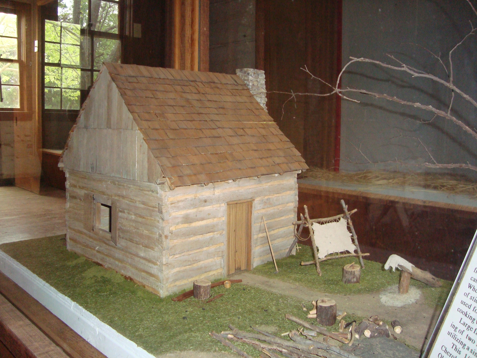 A model of a log cabin in a display case.