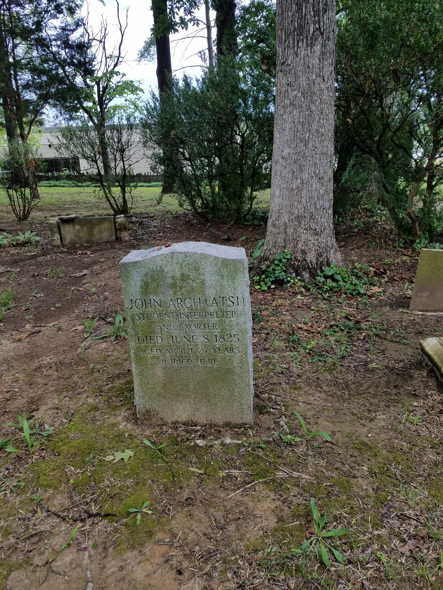 Two gravestones in a wooded area.