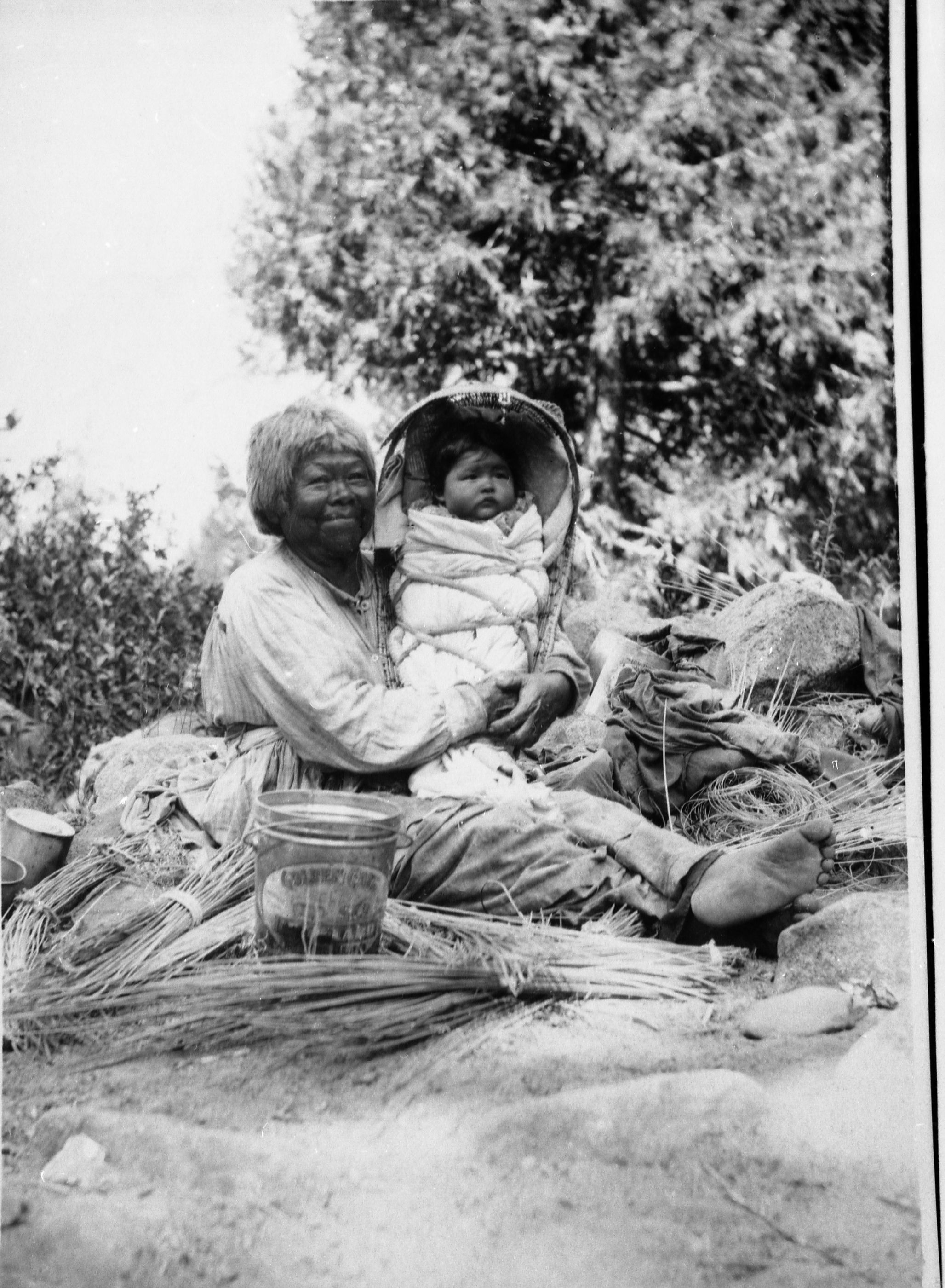 Lucy Brown surrounded by basket materials and Great Granddaughter Alice Roosevelt Wilson in a Miwok cradleboard. (Fig. 262, p. 140 Traditions & Innovations).