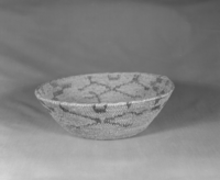 Private Collection. Object: Miwok basket. Dimensions: 12 x 3-3/4". Materials: Redbud, bracken fern, & bull pine. Technology: Single rod, fag ends trimmed on work face, moving ends trimmed on interior. Leftward coil direction. Rim overstitched three times through top rod with two back stitches at coil ending. Overstitched large clockspring start. Triangular design unit group in redbud, linear design units in bracken fern root. Collection History: Made by Matilda, 1920s. Photographed by Michael Dixon. Catalogued by Craig Bates and Barbara Beroza. Yosemite Collections, National Park Service.