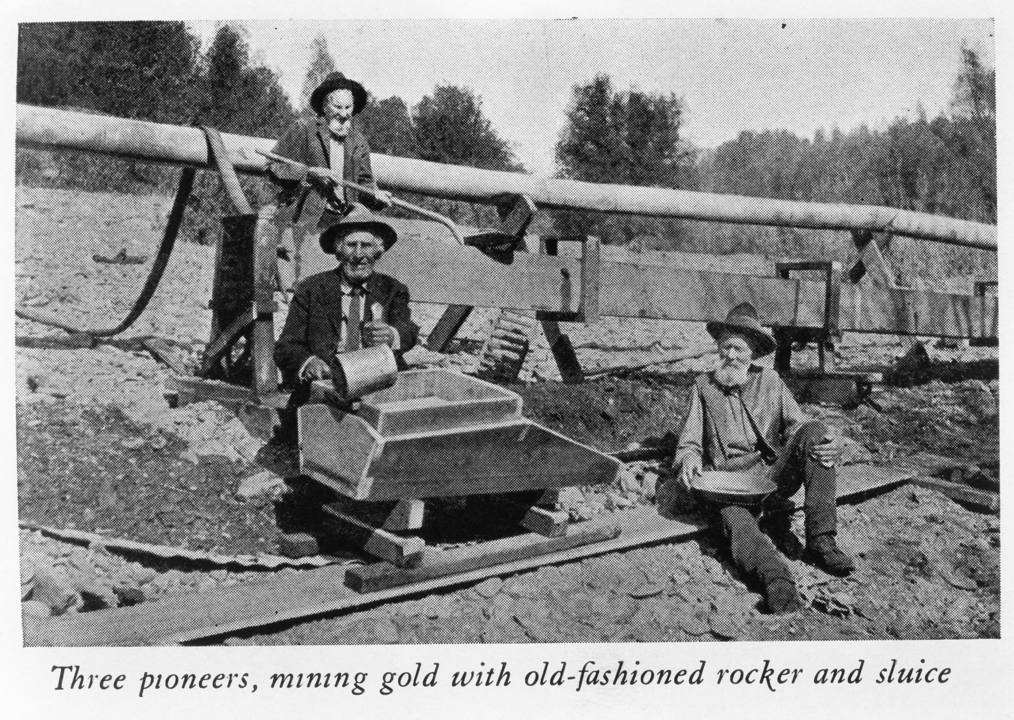 Three pioneers, mining gold with old-fashioned rocker and sluice.