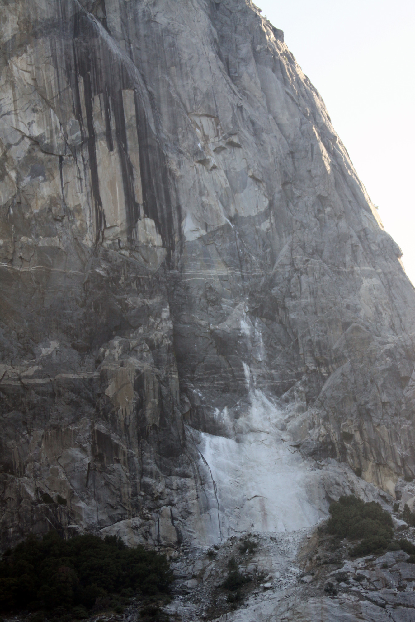 A close perspective of the impact marks and rock dust on cliff. Fresh rock debris on a brush covered ledge.