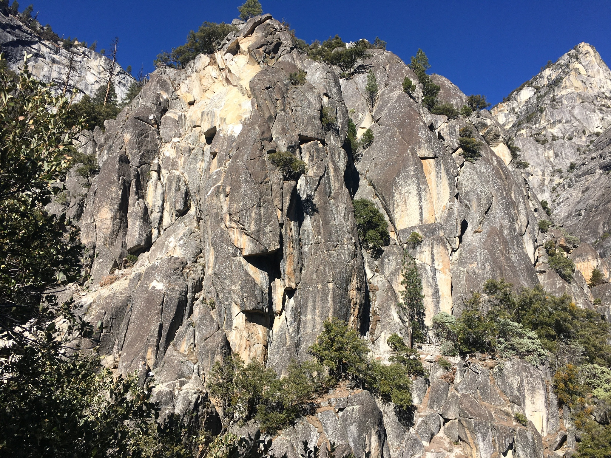 A rock fall source area at the top of a steep cliff, with impact areas and talus deposit on the slope below.