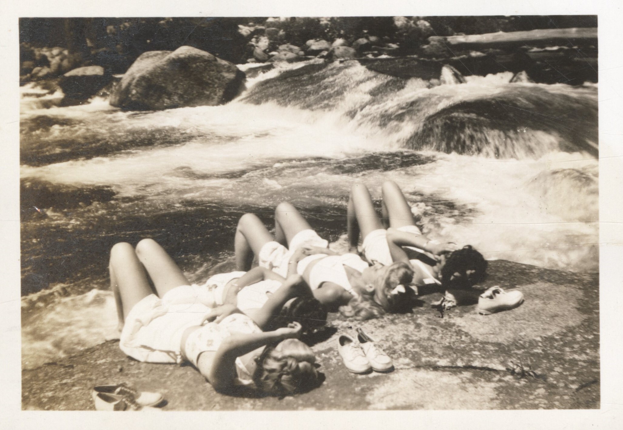 Four nurses sunning on a rock by the river