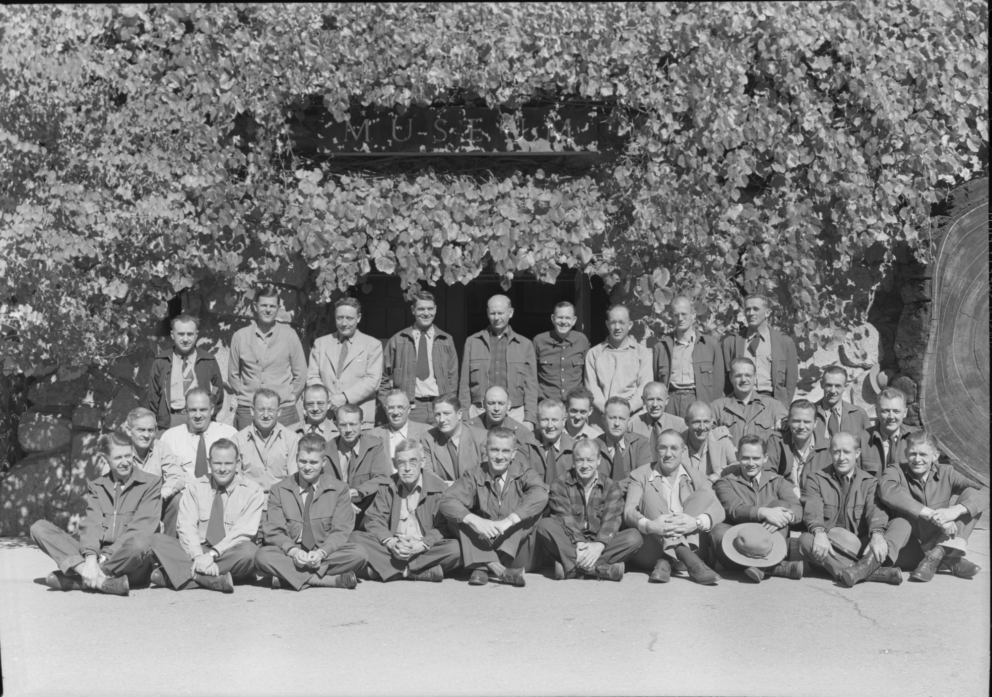 Building Fire School in front of Yosemite Museum. School term - October 18-27, 1948. LEFT TO RIGHT: BACK ROW: Bill Hackman, Mt. Rainier; Stanley McComan, Yosemite; Al Rose, Mt. Ranier, Chief Rang.; Homer Robinson, Yosemite, Asst. Chief; Elmer Fladmark, Glacier, Chief Rang.; Odin Johnson, Yosemite - Ranger; J. Leonard Volz, Mt. Ranier, Ranger; Floyd Dickinson, Olympic - Ranger. Paul Judge, Grand Teton, Chief Rang. MIDDLE ROW: W.R. Oakes, Olympic, Asst. Chief; Less Bodine, Lassen, Ranger; John L. Chambers, Wind Cave, Maint. Foreman; Maynard Barrows, Region 2, Forester; Lynn Coffin, Rocky Mtn. Dist. Ranger; Ted Ogsten, Death Valley, Chief Ranger; Clyde Gilbert, Crater Lake, Chief Ranger; Richard Nelson, Glacier Asst. Chief; Henry C. Schmidt,Sequoia, Dist. Ranger; L.M. Yansen, Ranier, Concessioner; John Jay, Yellowstone, Dist. Ranger; Lawrence Taylor, Yosemite, Concessioner; Floyd Towne, Ranier, Concessioner; Emil Ernst, Yosemite, Forester; Jack Dodd, Region 4 Forester; Lou Hallock, Yosemite Dist. Ranger; Henry R