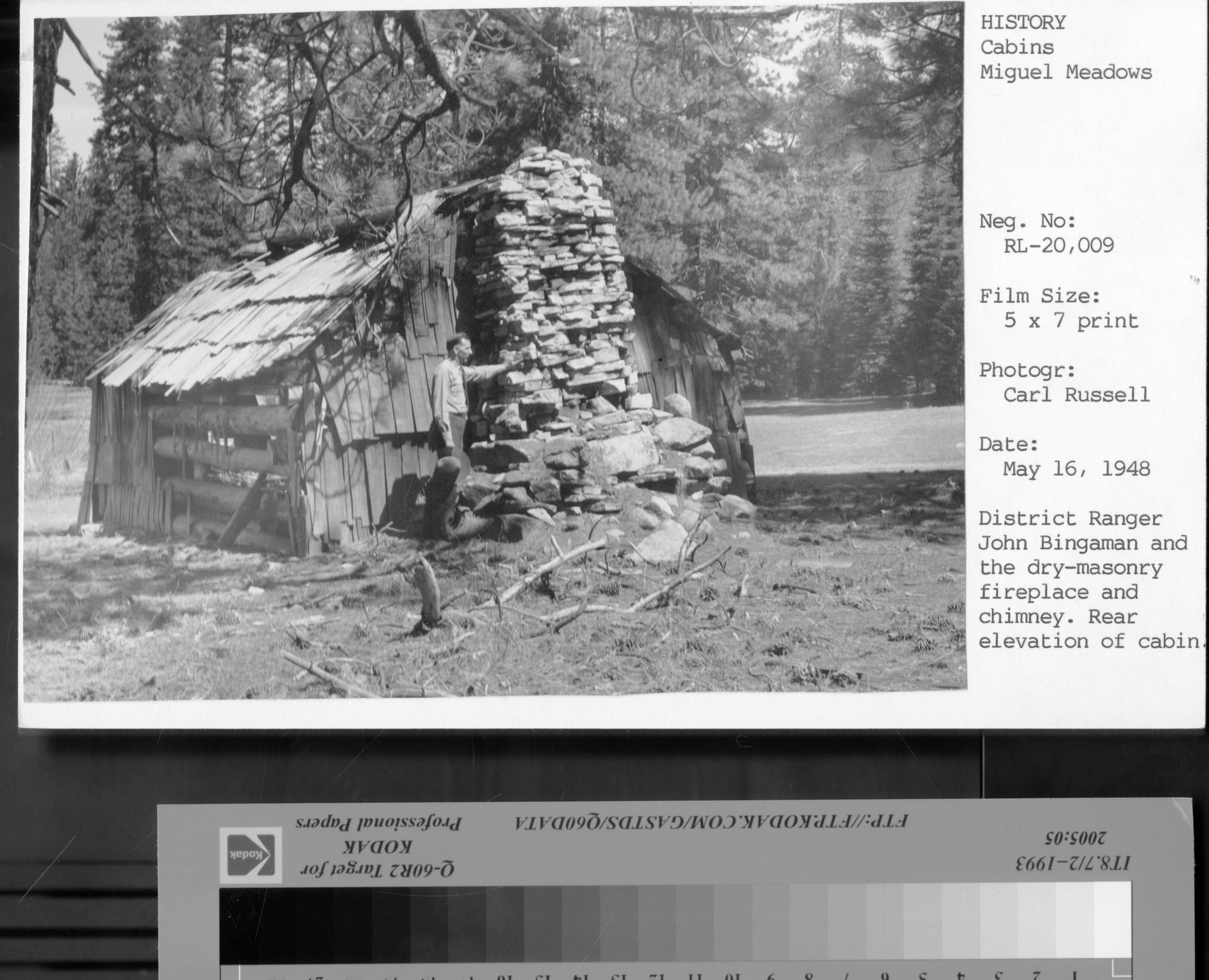 District Ranger John Bingaman and the dry-masonry fireplace and chimney. Rear elevation of cabin. [on Photo card]: No negative. Digital scan of a 5 x 7 print assigned to this number. June, 2011.
