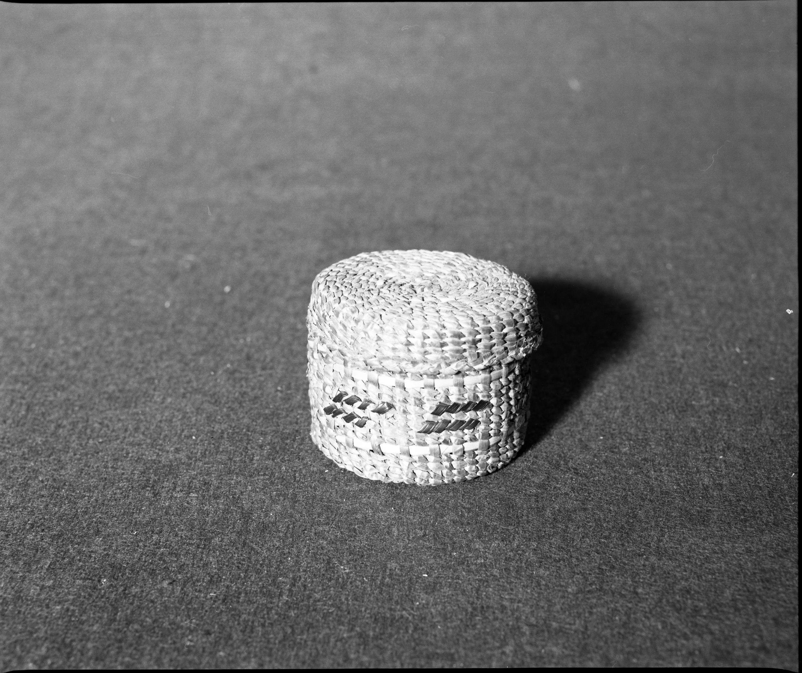 Marie Rozier Collection, Catalog No. 157. Object: Tshimshiam cover basket. Dimensions: 3 x 2-3/8". Materials: Red cedar bark, maidenhair fern stem, grass. Technology: Down to right slant of turns. Collection History: From Alaska Native Arts & Crafts. Bought by Mary Baker ca. 1970. Photographed by Michael Dixon, December 1982. Catalogued by Craig Bates and Barbara Beroza. Yosemite Collections, National Park Service.