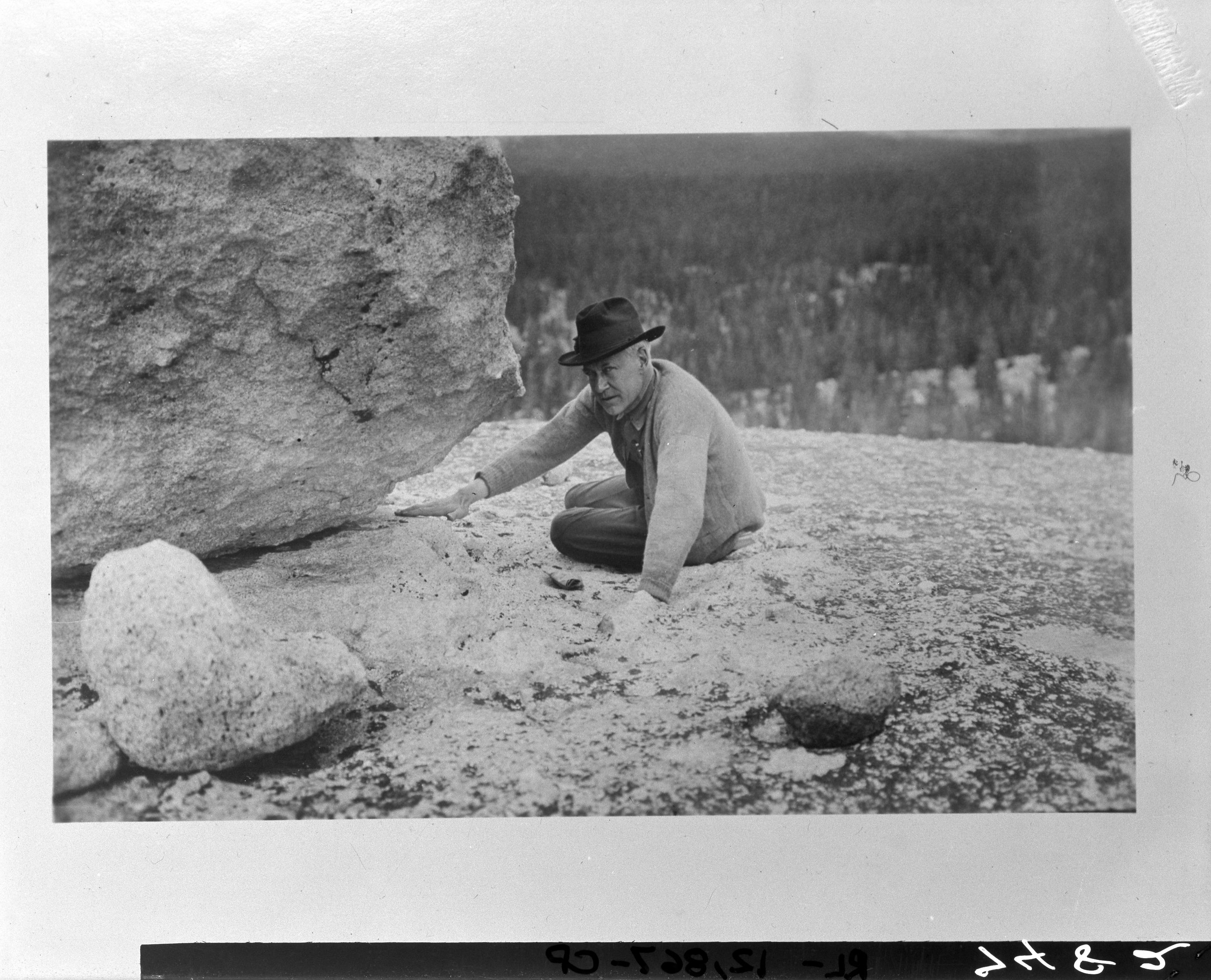 Stephen T. Mather at Tuolumne Meadows, Yosemite. Looking at a glacial erratic on the polished granite of Lembert Dome.