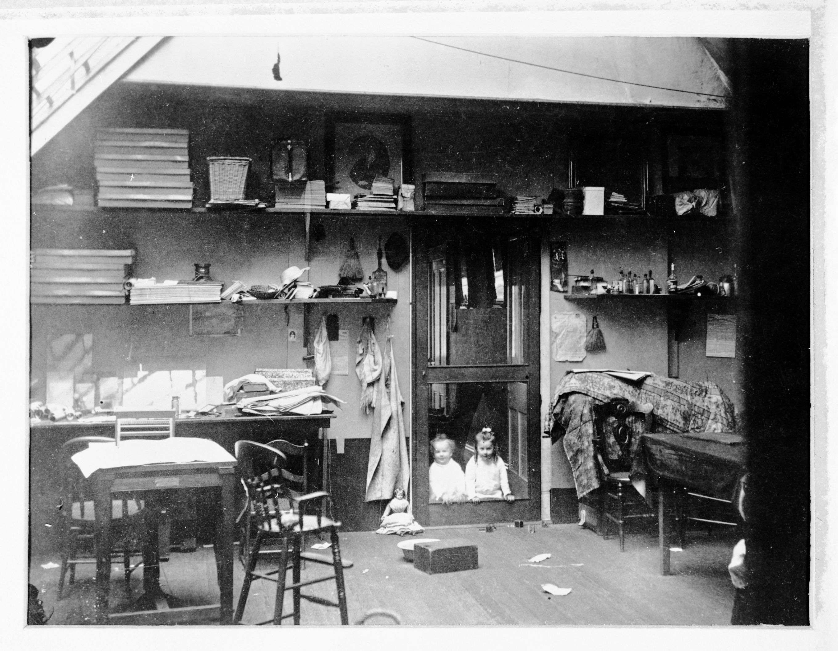 Also RL-14,547. C.E. Watkins workroom and his children looking in. Interior of Carlton E. Watkins studio on Montgomery St. showing his children Julia C. and Colis P. in doorway AND doll beside doorway named "Armenta Clementina Josephina Watkins".