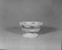 Private Collection. Object: Miwok basket. Dimensions: 5 1/2 x 3 1/4". Materials: Redbud, split shoot that could be bull pine. Technology: Pedestal base was made and attached by two or three stitches. Collection History: Made for the owner when she was a child, by Matilda, a Sonora Miwok, c. 1920. Photographed by Michael Dixon. Catalogued by Craig Bates and Barbara Beroza. Yosemite Collections, National Park Service.