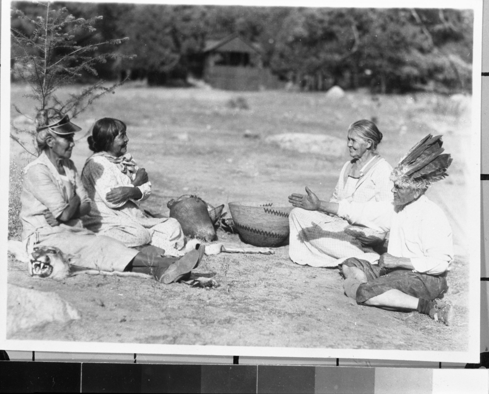 Native American hand game. L to R: Sally Ann, Maggie Howard, "Grandma", and Bill Dad. Bill Dad calls "put-ka". The mountain lionskin and baskets are from the YNP collections.