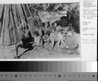 White children being entertained by a Native American's radio. Norman James dailing radio.