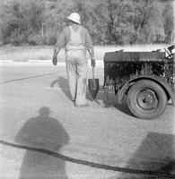 Man filling cracks in road along the scenic canyon drive near the Grotto.