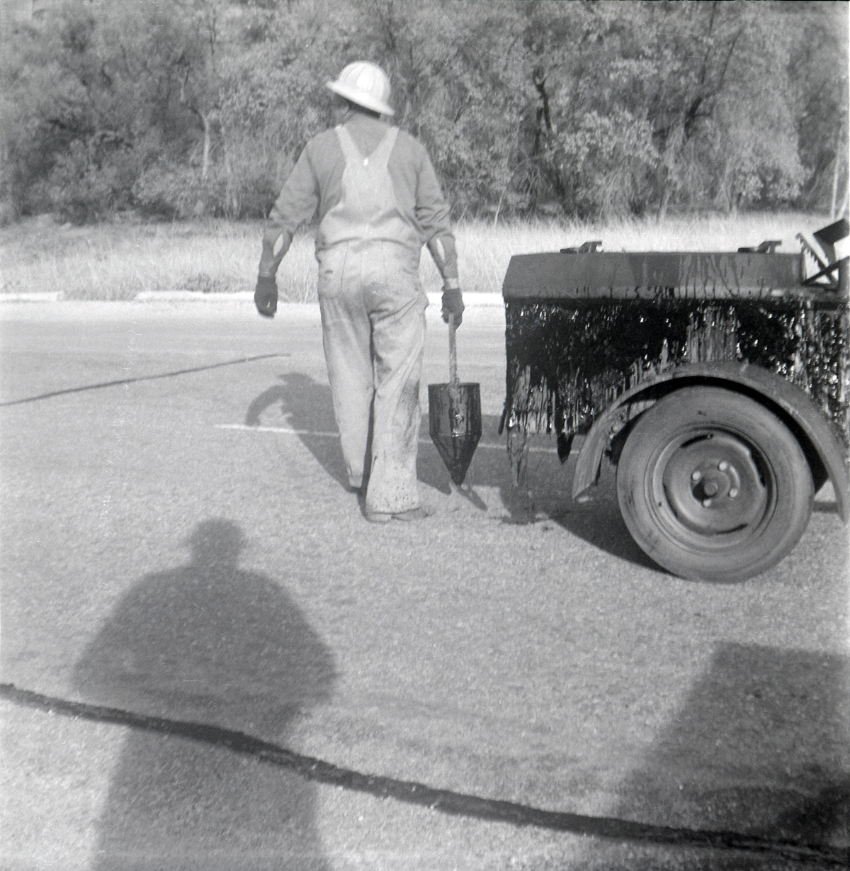 Man filling cracks in road along the scenic canyon drive near the Grotto.