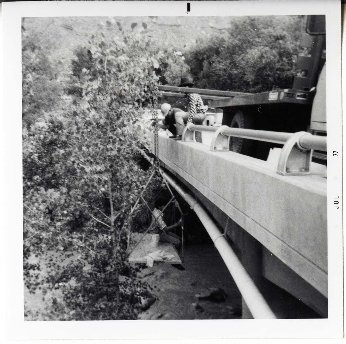 Workers place pipe on side of bridge during the Watchman housing utility project.
