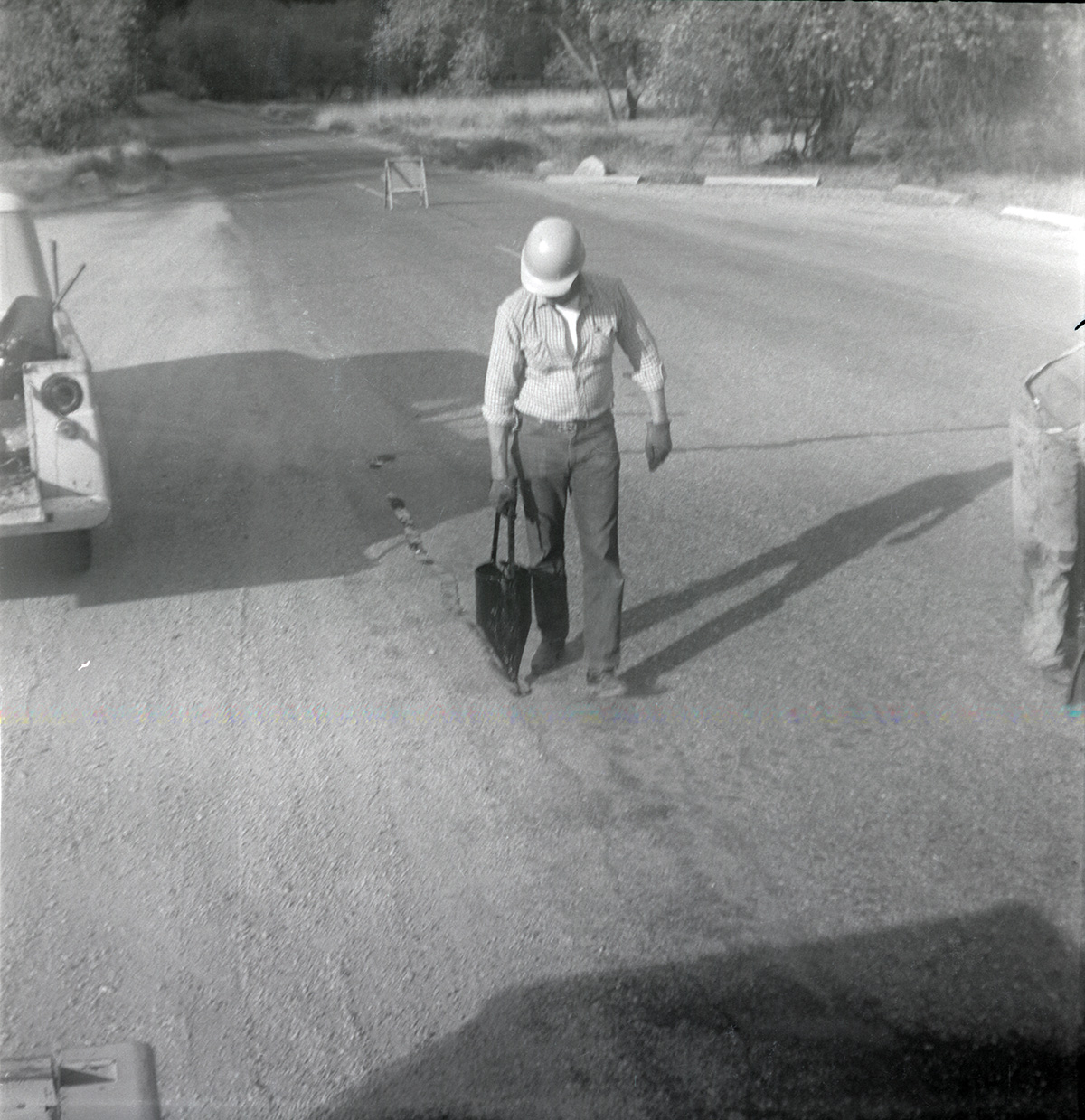 Man filling cracks in road along the scenic canyon drive near the Grotto.