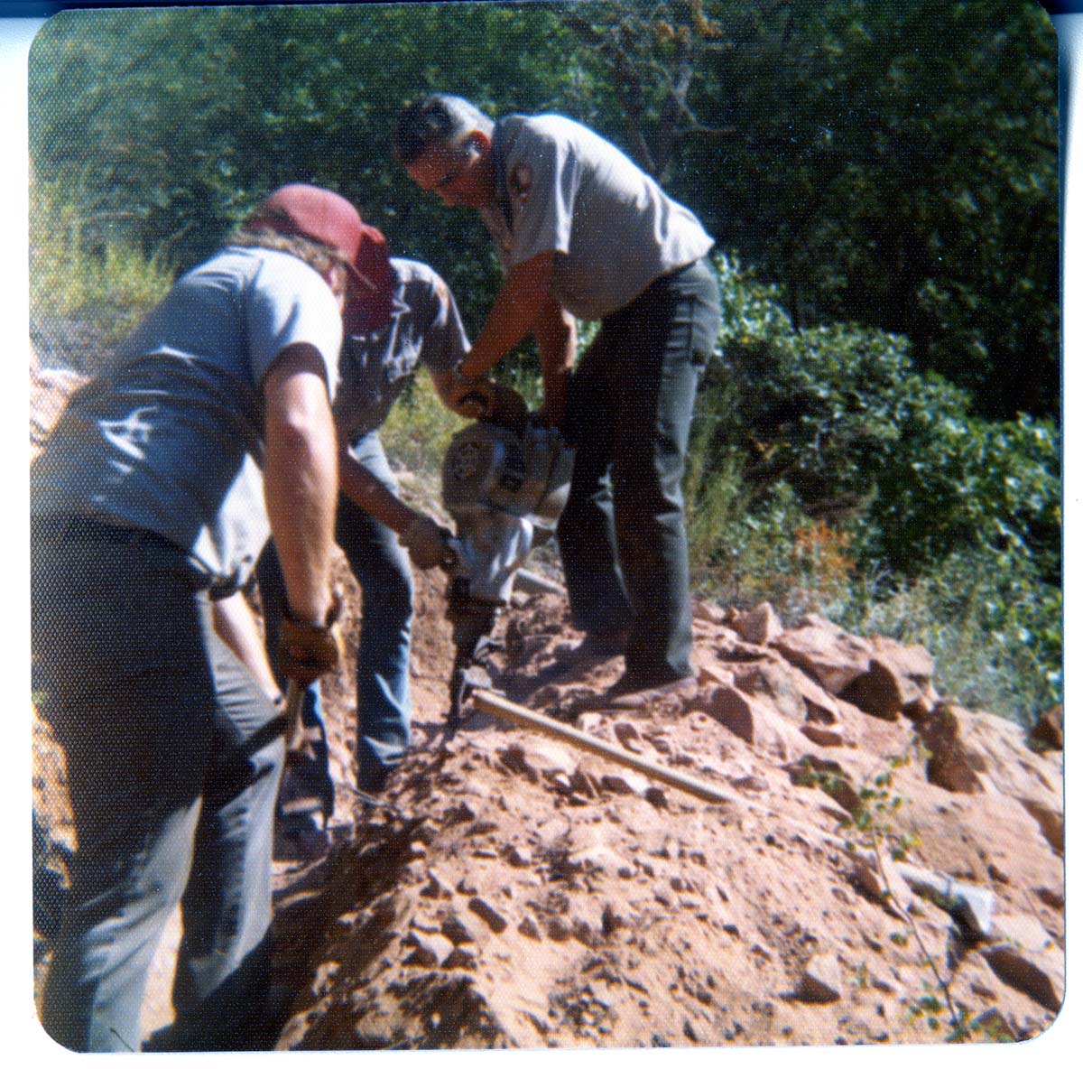 Workers using jackhammer to excavate ditch.