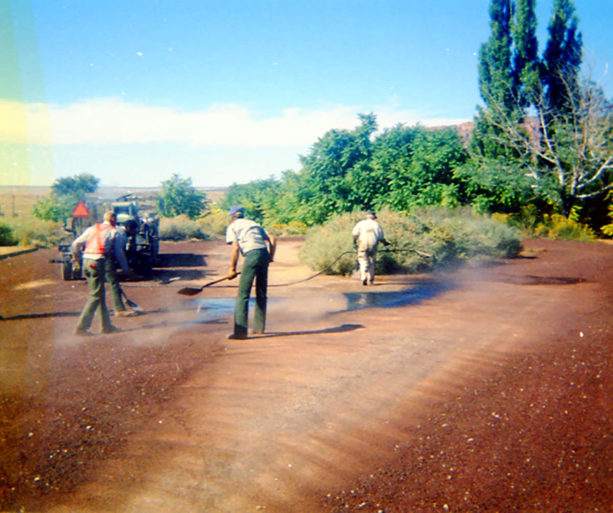 Color Photos of workers chip sealing the parking lot at Pipe Spring.