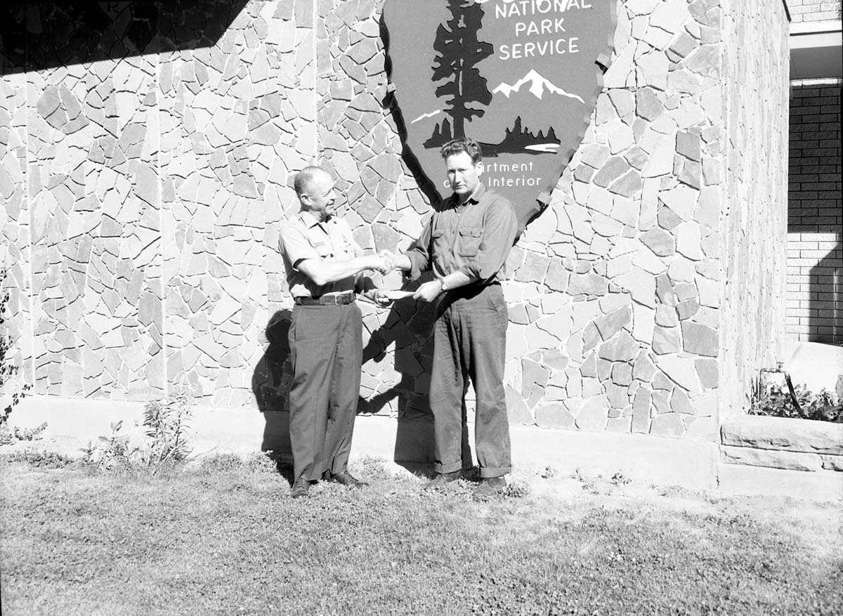 Superintendent Oberhansley presenting award to Donald DeMille for superior performance of duty, in front of Mission 66 Visitor Center and Museum.