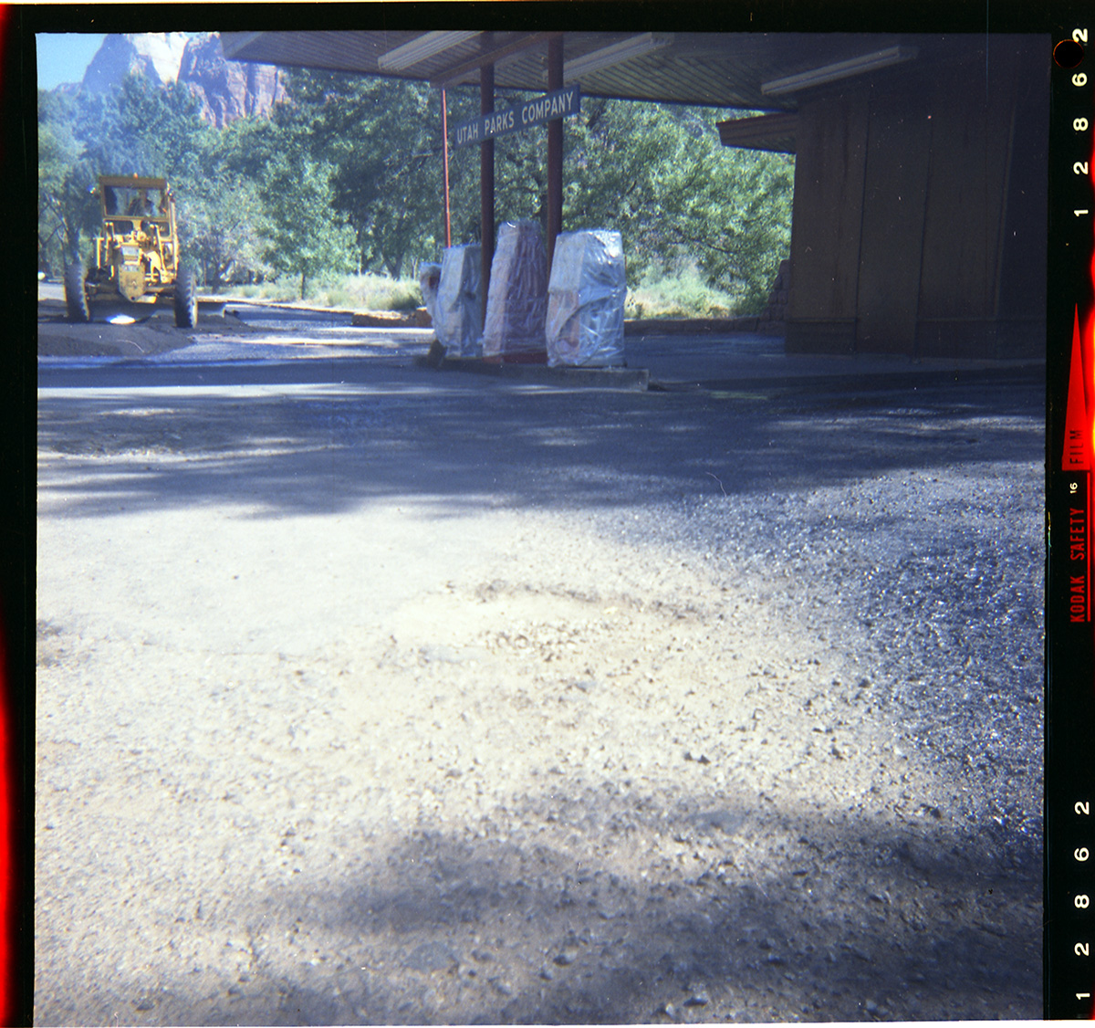 Tractor performing shoulder work along route 2 parking areas. Next to Utah Parks Company fuel pumps.