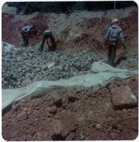 Men placing rock pile over tarp during road work/repair in Kolob Canyon.
