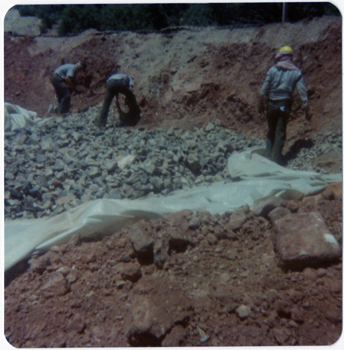 Men placing rock pile over tarp during road work/repair in Kolob Canyon.